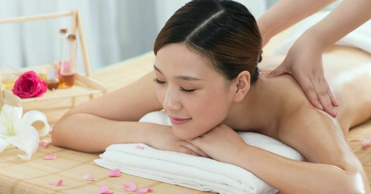 オイルマッサージを受けている日本人女性が顎を両手の上に載せています。