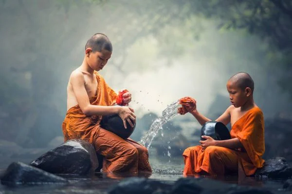 タイのお坊さんの子供が滝で座り込んでいる